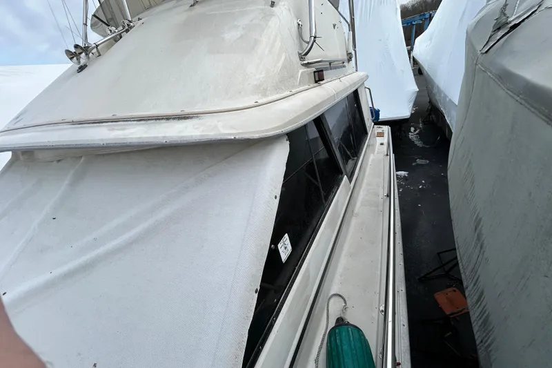 Slide: The Image of 1983 Silverton 34 Convertible boat covered in protective wrap, docked among other boats. - 23