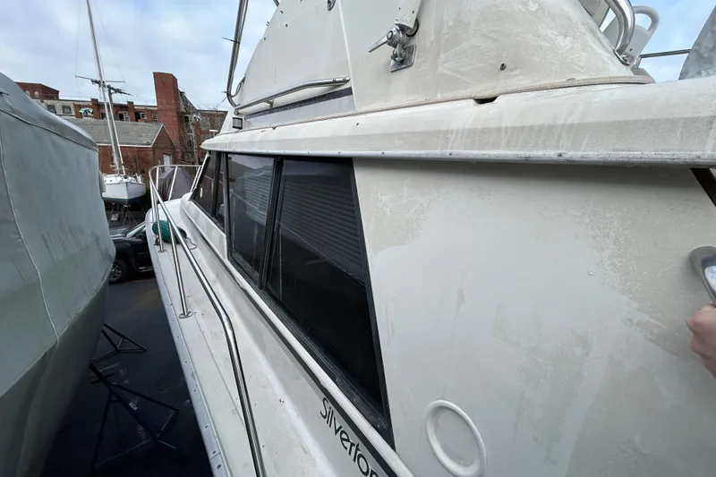 Slide: The Image of 1983 Silverton 34 Convertible boat docked, showing side view and windows. - 24