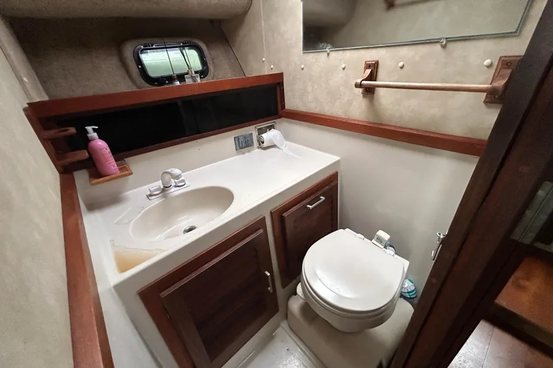 Slide: The Image of 1983 Silverton 34 Convertible yacht bathroom with sink, toilet, and wooden cabinetry. - 34