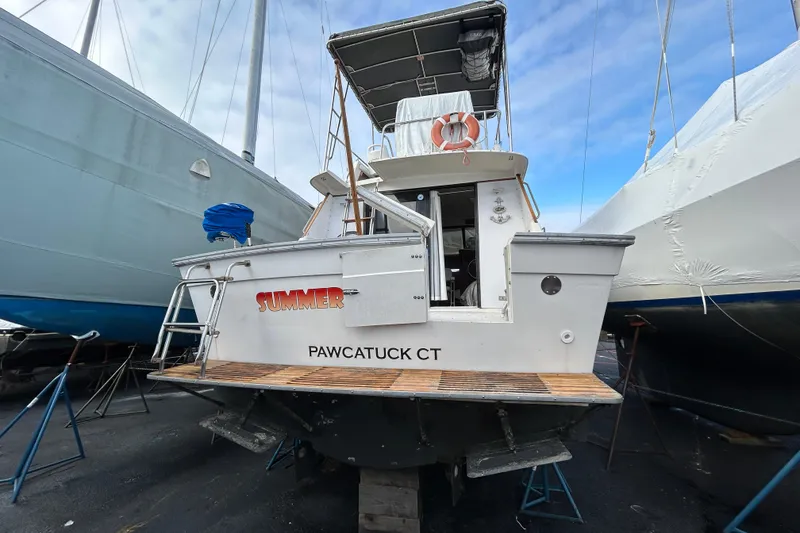 Slide: The Image of 1983 Silverton 34 Convertible boat in dry dock, Pawcatuck CT, with blue sky background. - 7