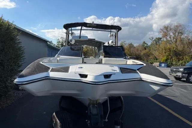 Slide: The Image of 2013 Malibu Wakesetter 24 MXZ boat on trailer, parked outdoors under a partly cloudy sky. - 3
