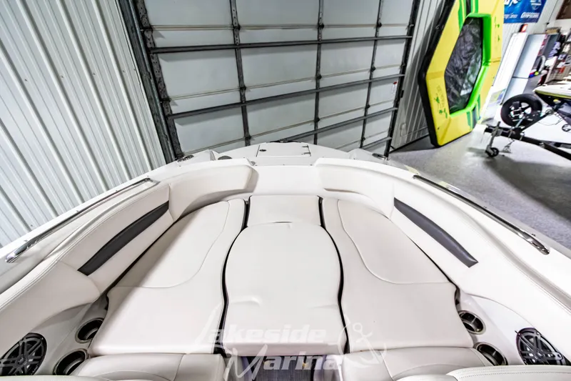 Slide: The Image of 2017 Chaparral 244 Sunesta boat interior with white seating in a garage setting. - 36