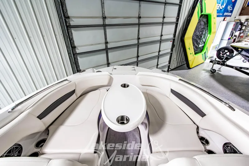 Slide: The Image of 2017 Chaparral 244 Sunesta boat interior with white seating and table in a garage. - 39