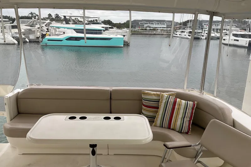 Slide: The Image of 2002 Sea Ray 480 Motor Yacht interior with seating, table, and colorful cushions in marina setting. - 7