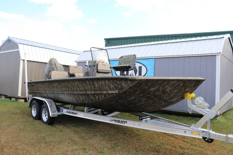 The Image of 2026 Sea Ark Phantom 20XV CC boat on trailer, camo design, parked near sheds. - 0