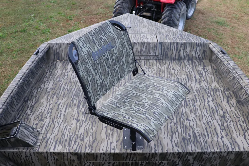 Slide: The Image of 2026 SeaArk Phantom 20XV CC boat with camouflage seating and deck, parked on grass. - 2