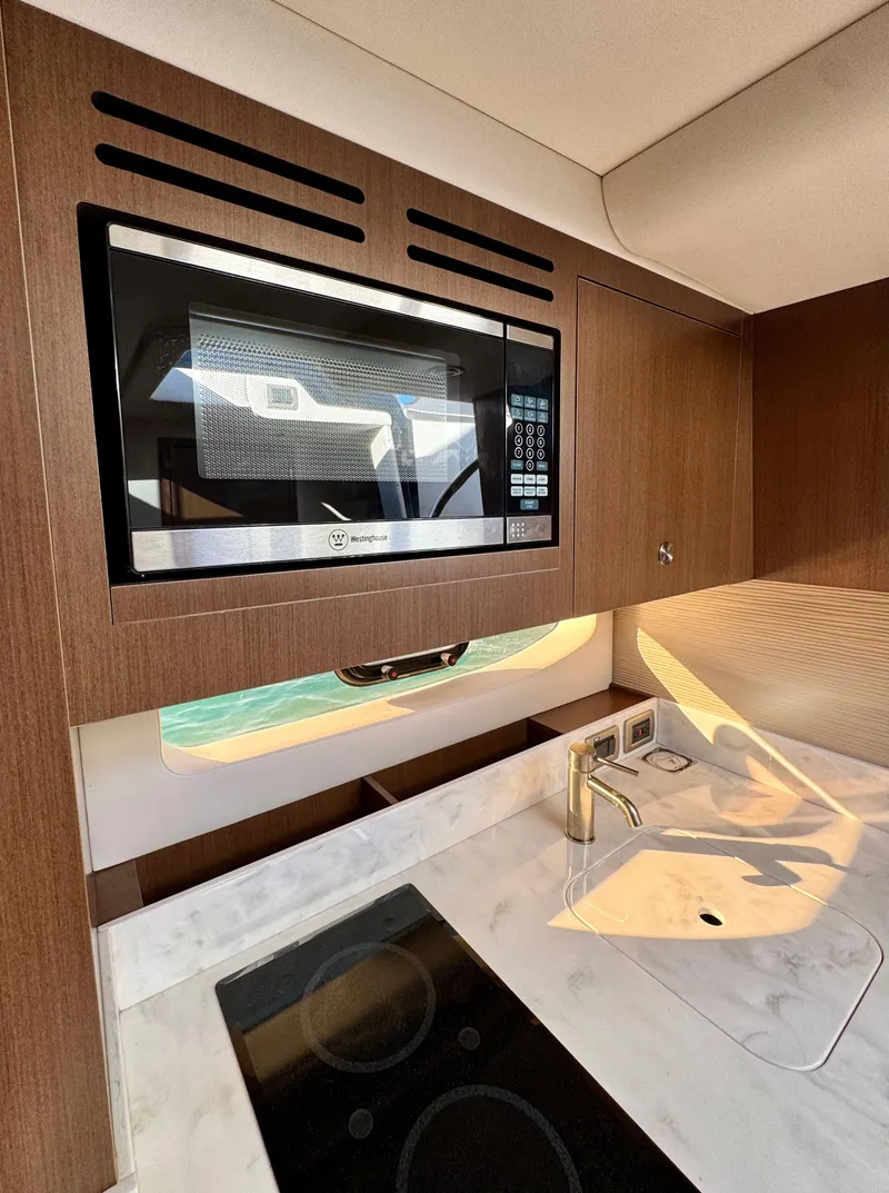 Slide: The Image of Interior of 2018 Sea Ray 350 DAC with modern kitchen amenities, including microwave and stovetop. - 22