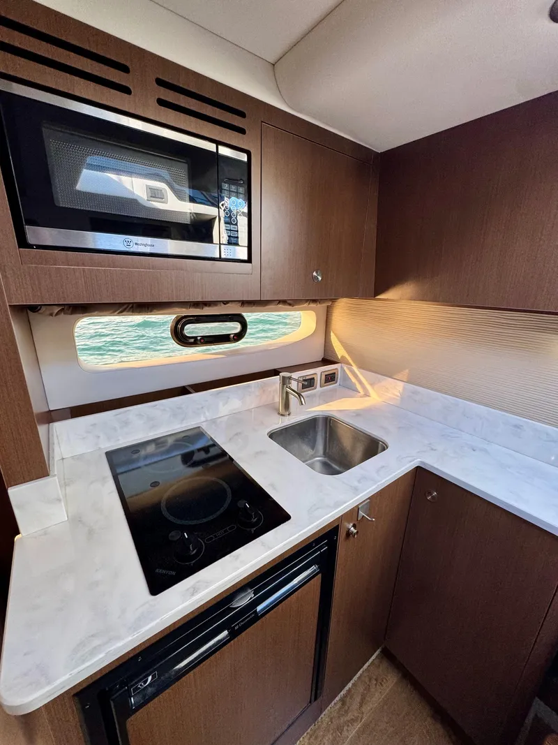 Slide: The Image of 2018 Sea Ray 350 DAC kitchen with stove, sink, and microwave. - 24