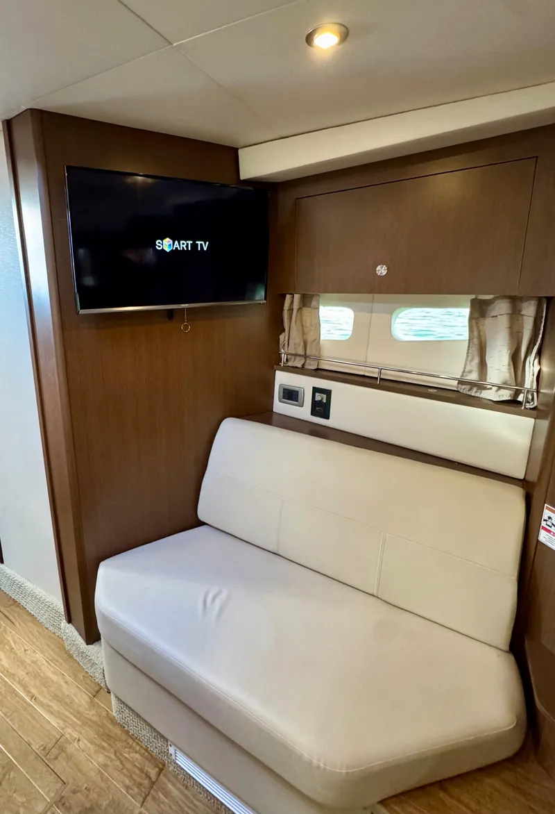 Slide: The Image of 2018 Sea Ray 350 DAC interior with smart TV and beige seating. - 25