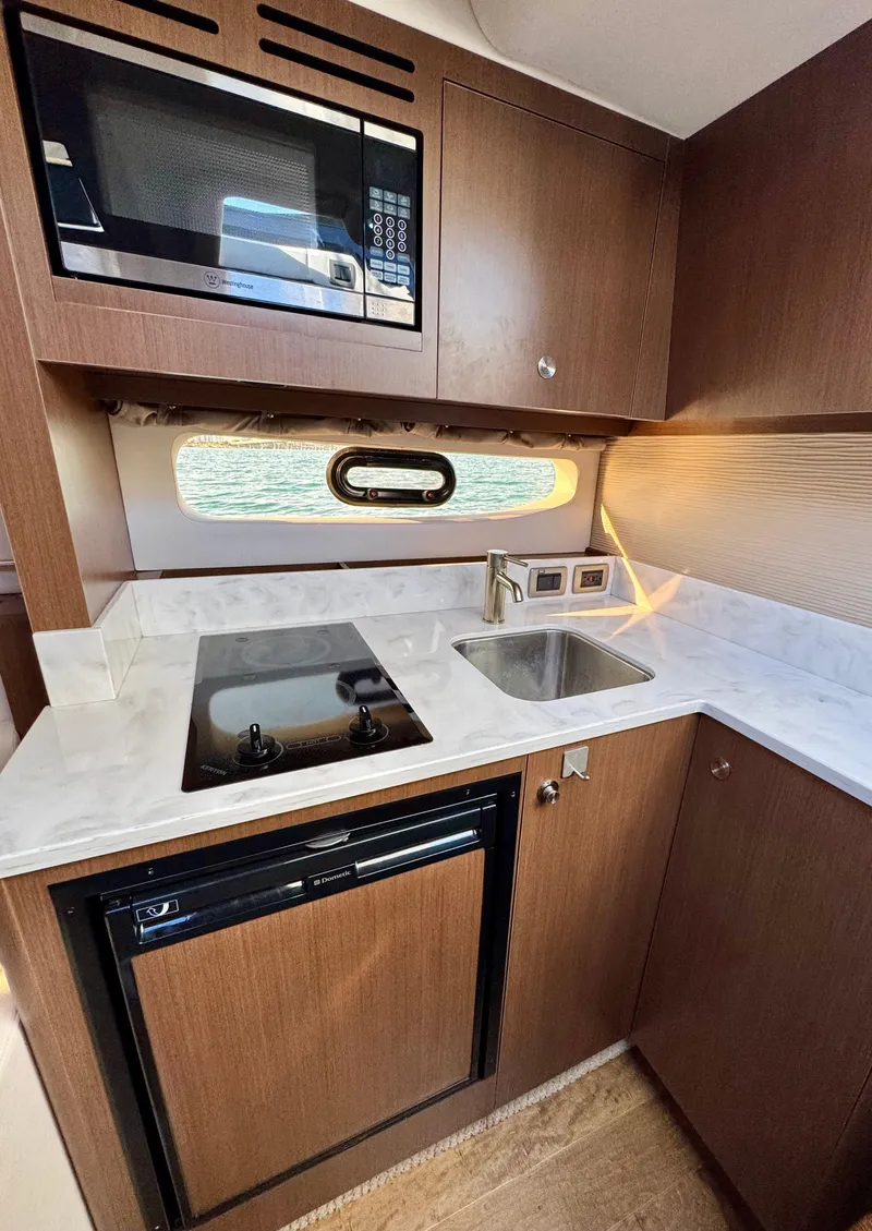 Slide: The Image of 2018 Sea Ray 350 DAC yacht kitchen with microwave, stove, sink, and window. - 33