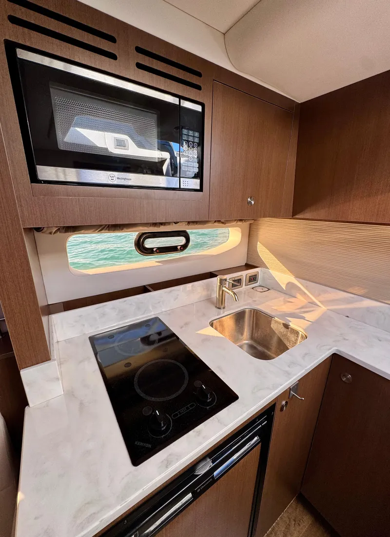 Slide: The Image of 2018 Sea Ray 350 DAC yacht kitchen with stove, microwave, and sink. - 34