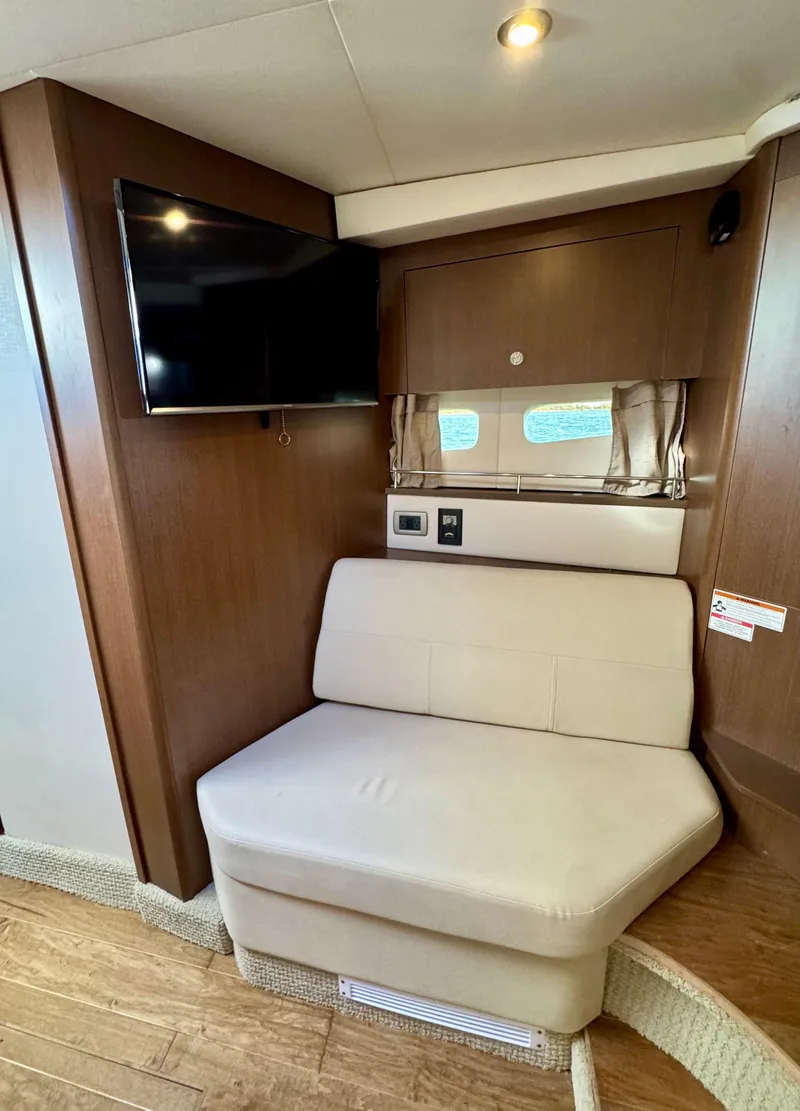 Slide: The Image of 2018 Sea Ray 350 DAC interior with beige seating, wall-mounted TV, and wood accents. - 35