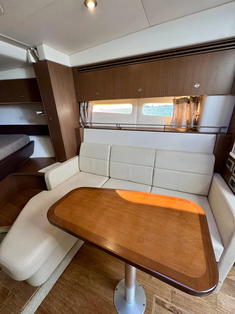Slide: The Image of 2018 Sea Ray 350 DAC interior with white seating and wooden table. - 37
