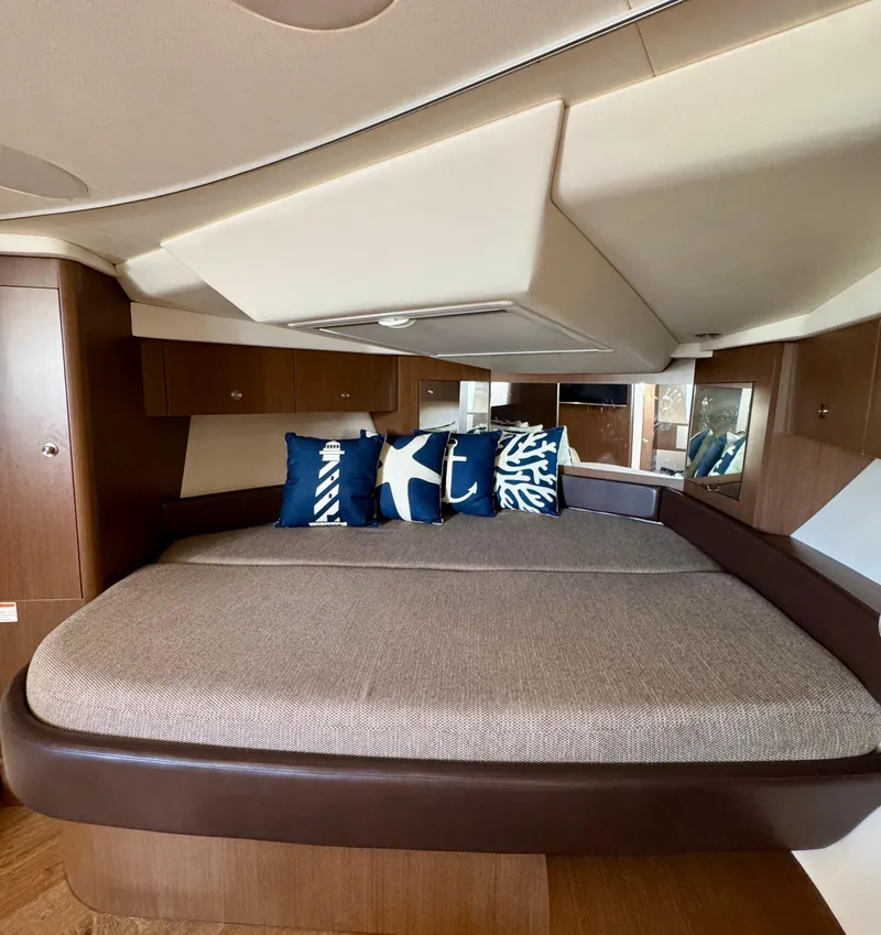 Slide: The Image of 2018 Sea Ray 350 DAC cabin interior with nautical-themed pillows on a cozy bed. - 38