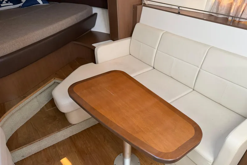 Slide: The Image of Interior of 2018 Sea Ray 350 Sundancer with white seating and wooden table. - 43