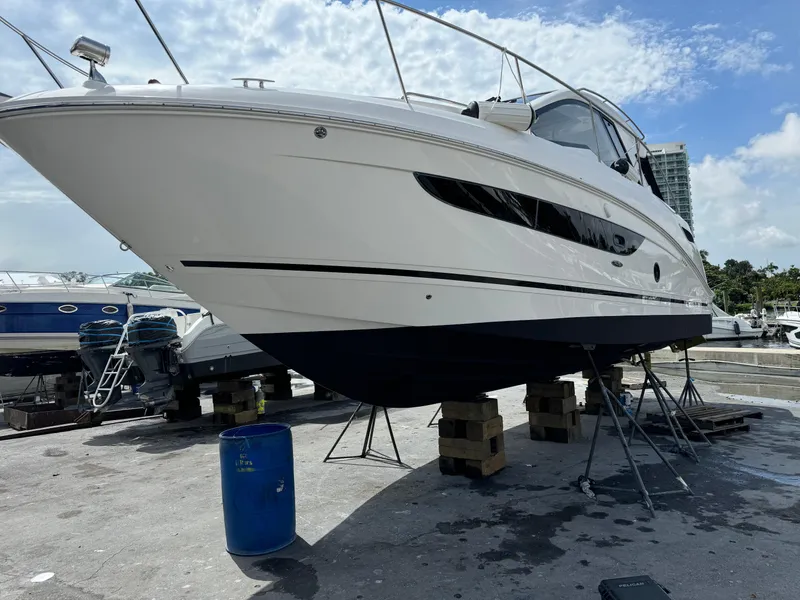 Slide: The Image of 2018 Sea Ray 350 DAC yacht on dry dock, supported by stands, under a partly cloudy sky. - 49