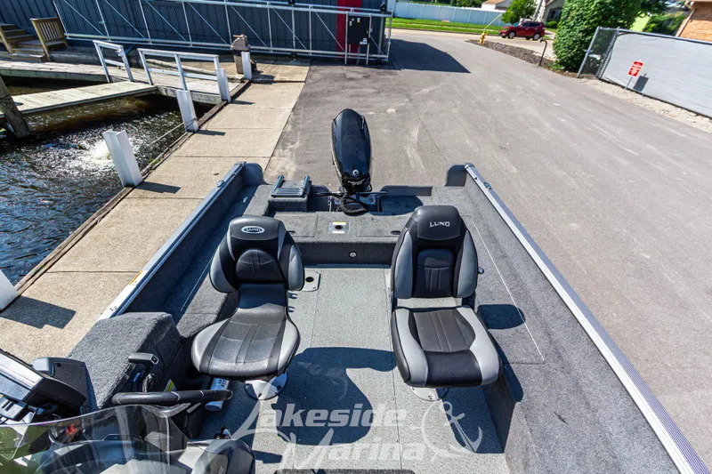 Slide: The Image of 2016 Lund 1675 Impact XS SS boat interior with two black seats at dockside. - 23