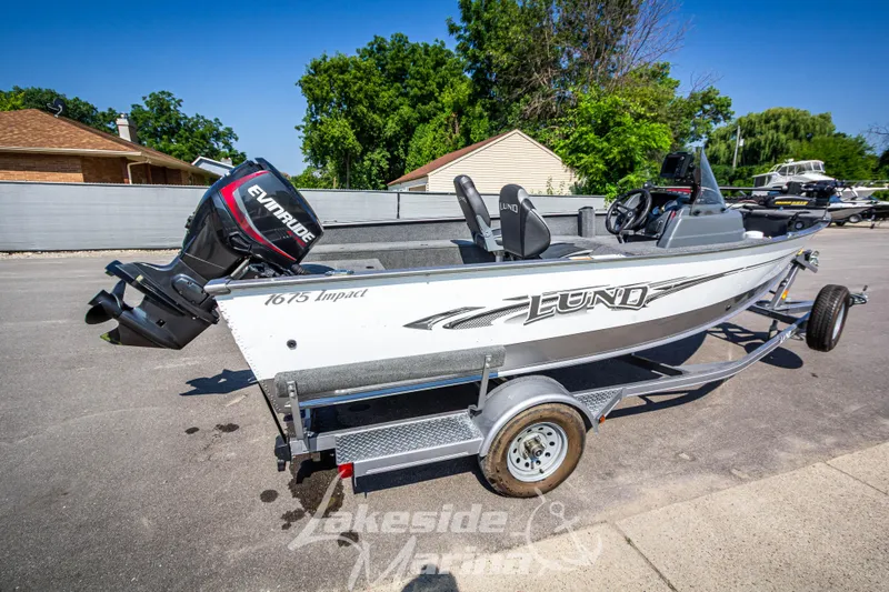 Slide: The Image of 2016 Lund 1675 Impact XS SS boat on trailer with Evinrude motor, parked outdoors. - 3