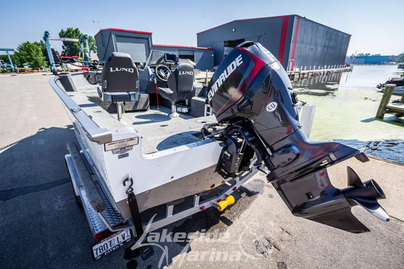 Slide: The Image of 2016 Lund 1675 Impact XS SS boat with Evinrude motor, docked near a marina. - 6