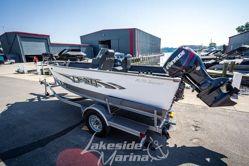 Slide: The Image of 2016 Lund 1675 Impact XS SS boat on trailer at marina, featuring Evinrude motor. - 7