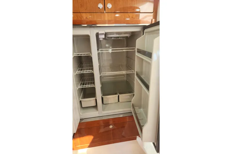 Slide: The Image of Open refrigerator inside 2017 Intrepid 475 Sport Yacht, featuring wooden cabinetry and spacious shelving. - 35