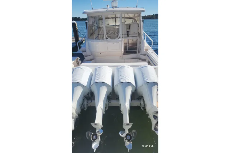 Slide: The Image of 2017 Intrepid 475 Sport Yacht with four covered outboard engines, docked on calm water. - 9