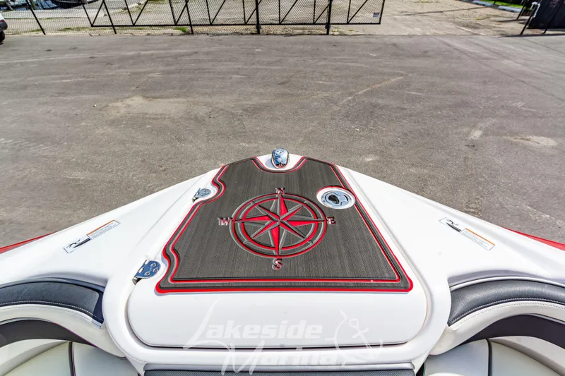 Slide: The Image of 2016 Yamaha Boats 242 Limited S E-Series bow with compass design, parked on pavement. - 40