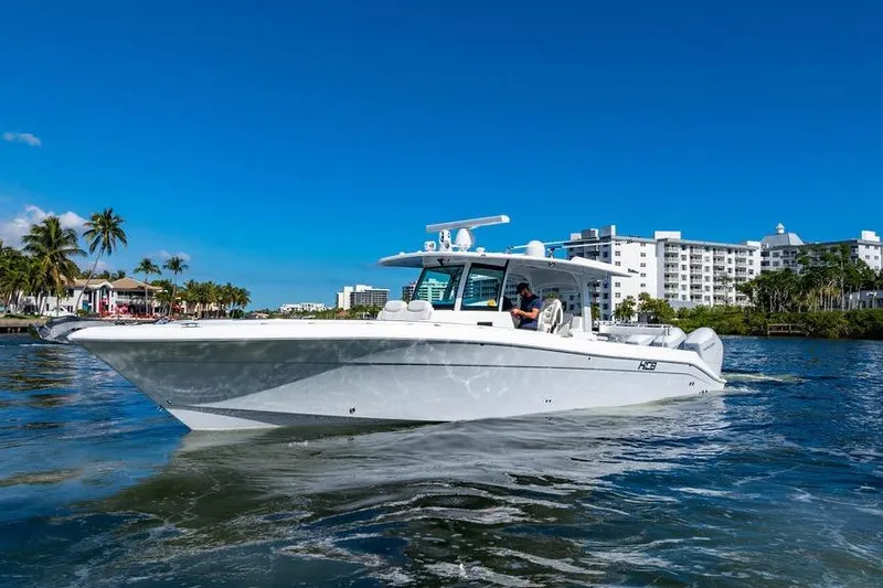 The Image of 2024 HCB 42 Lujo boat cruising near waterfront buildings and palm trees. - 0
