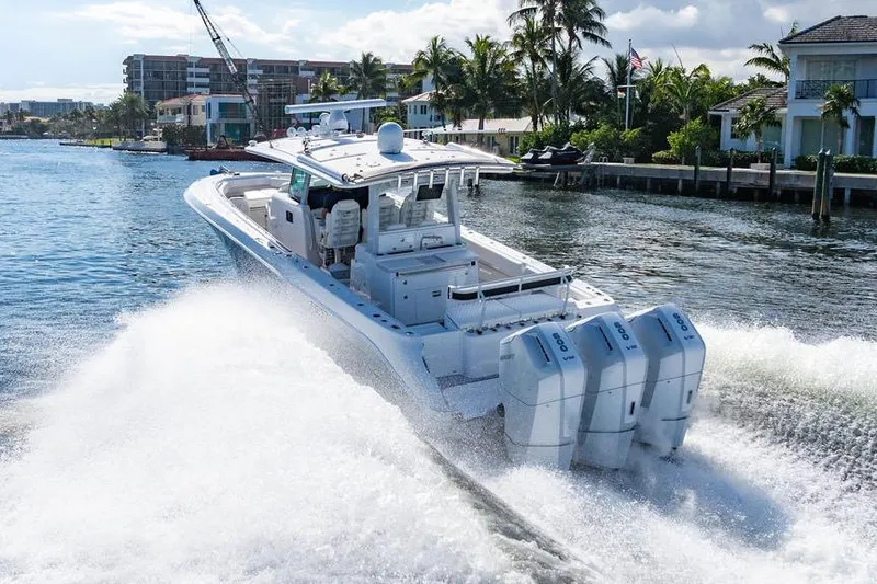 Slide: The Image of 2024 HCB 42 Lujo boat cruising on a sunny waterway with palm trees. - 15