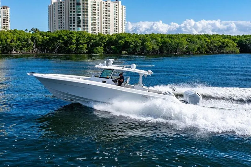 Slide: The Image of 2024 HCB 42 Lujo boat cruising on water near city skyline and lush greenery. - 17