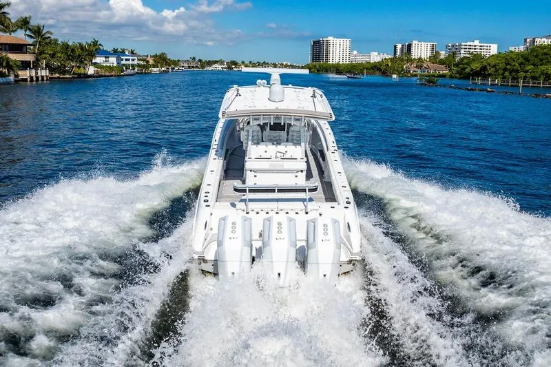 Slide: The Image of 2024 HCB 42 Lujo boat cruising on a scenic waterway with city skyline. - 19