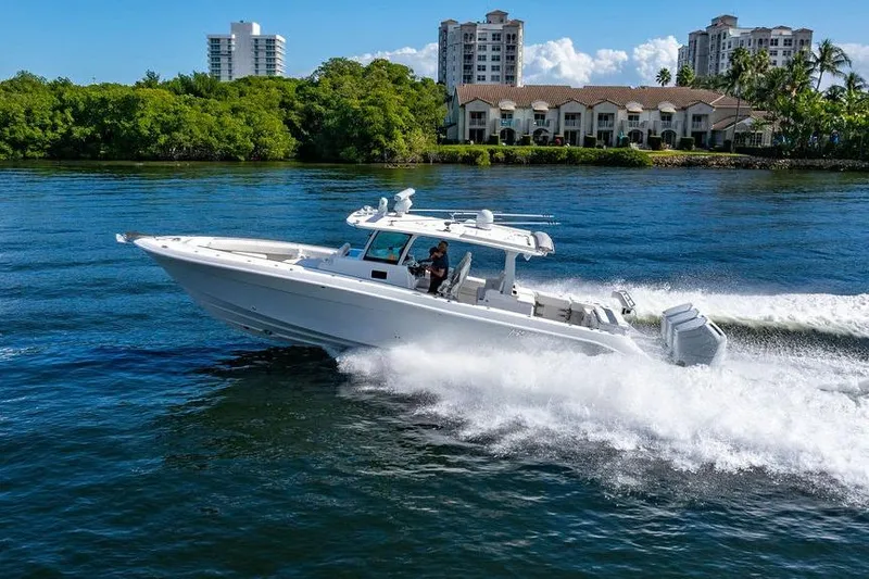 Slide: The Image of 2024 HCB 42 Lujo boat cruising on water near luxury waterfront homes. - 21