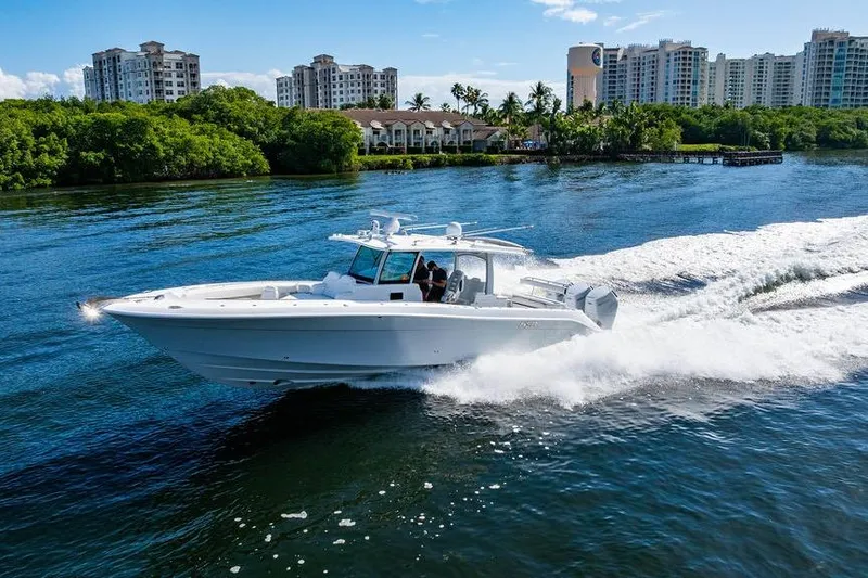Slide: The Image of 2024 HCB 42 Lujo boat cruising on a scenic waterway with city skyline backdrop. - 22
