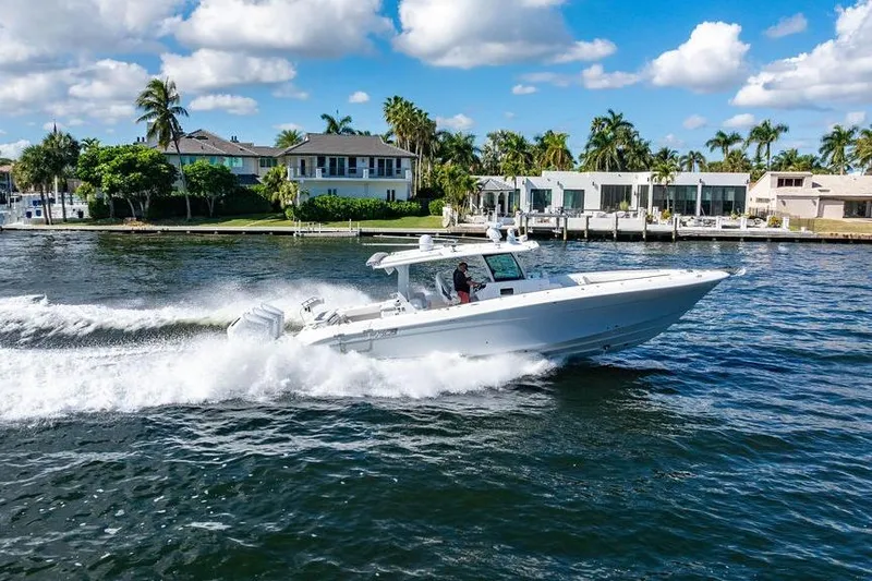 Slide: The Image of 2024 HCB 42 Lujo boat cruising on a sunny waterfront with luxury homes. - 25