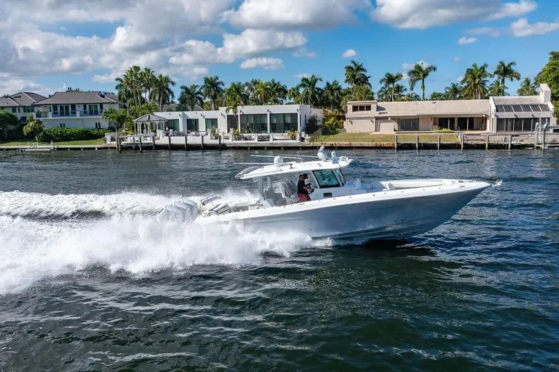 Slide: The Image of 2024 HCB 42 Lujo boat cruising on a sunny waterfront with modern homes. - 26