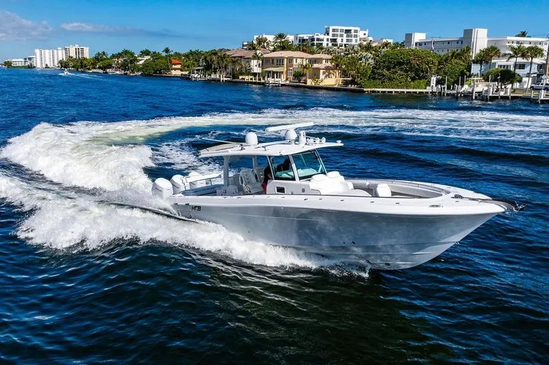 Slide: The Image of 2024 HCB 42 Lujo boat cruising on a sunny waterfront with luxury homes. - 28