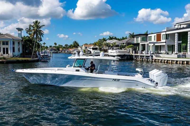 Slide: The Image of 2024 HCB 42 Lujo boat cruising in a scenic waterfront neighborhood. - 3