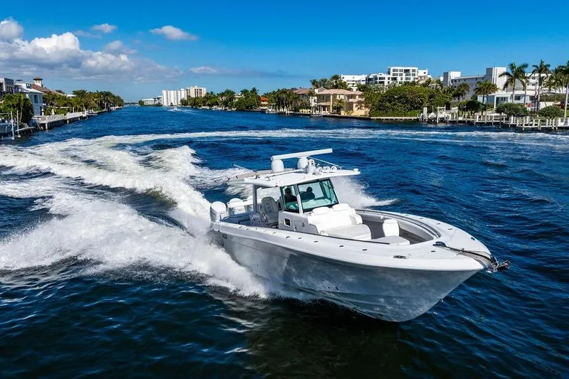 Slide: The Image of 2024 HCB 42 Lujo boat cruising on a sunny waterway with luxury homes. - 30