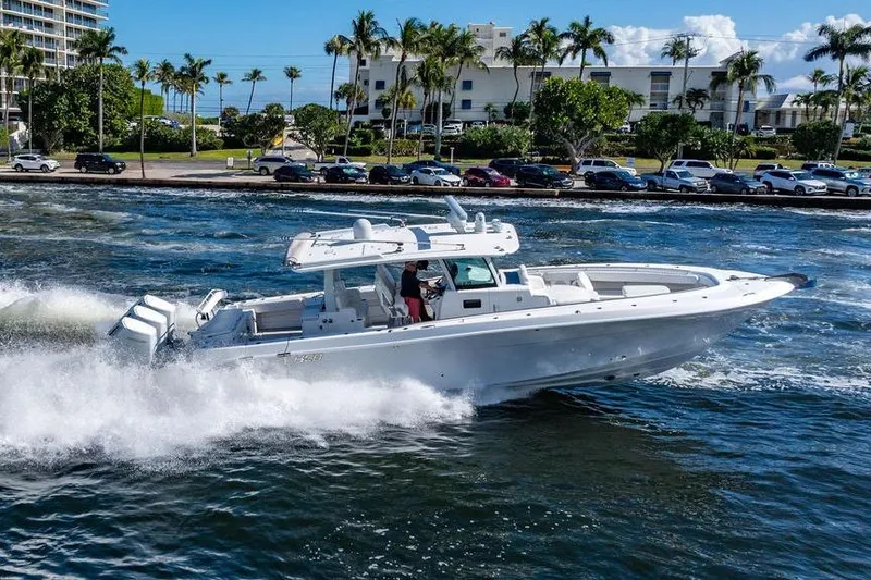 Slide: The Image of 2024 HCB 42 Lujo boat cruising on water near a coastal cityscape. - 31