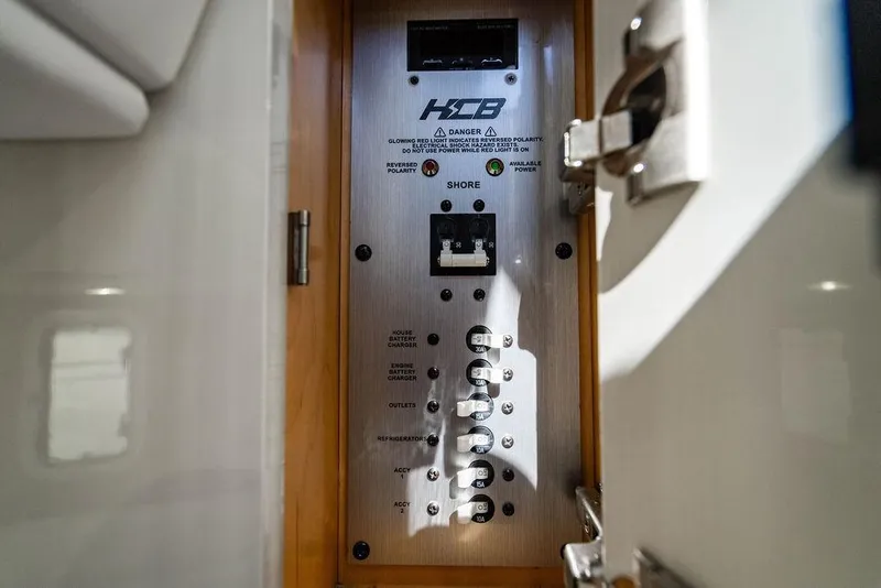 Slide: The Image of Electrical panel inside 2024 HCB 42 Lujo boat, showcasing circuit breakers and controls. - 44