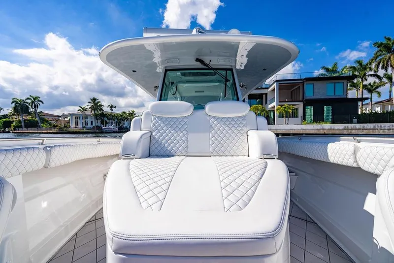 Slide: The Image of 2024 HCB 42 Lujo luxury boat with plush seating, docked near waterfront homes. - 61