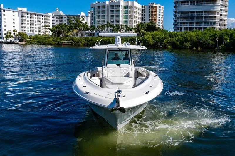 Slide: The Image of 2024 HCB 42 Lujo boat cruising near waterfront buildings and lush greenery. - 8