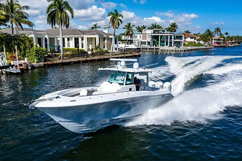 Slide: The Image of 2024 HCB 42 Lujo boat cruising on a sunny waterfront with palm trees. - 9