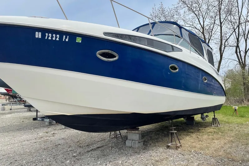 Slide: The Image of 2007 Bayliner 325 boat on stands, blue and white hull, outdoors. - 4