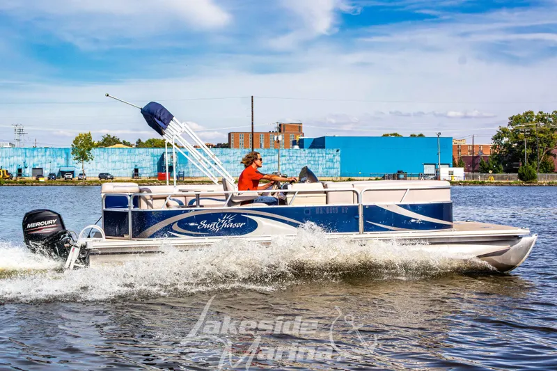 The Image of 2013 SunChaser DS22 pontoon boat cruising on a sunny day with blue buildings in the background. - 1