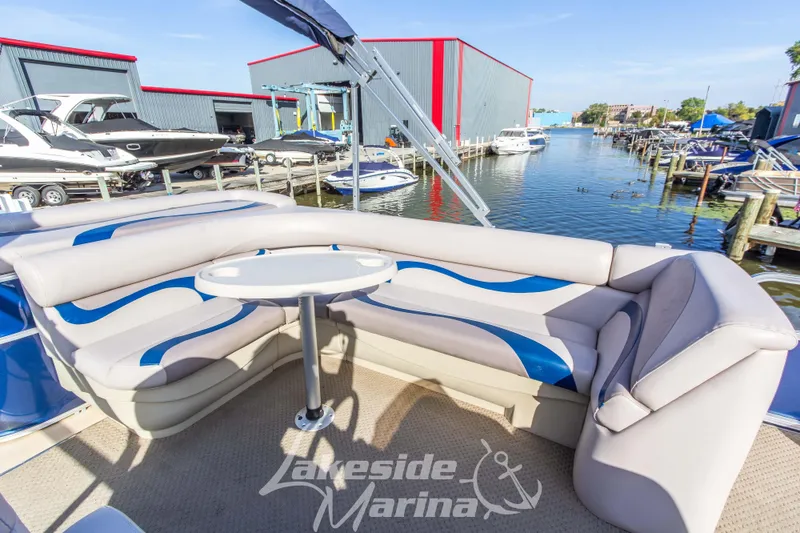 Slide: The Image of Pontoon boat interior with curved seating, table, and marina view. SunChaser DS22, 2013 model. - 19