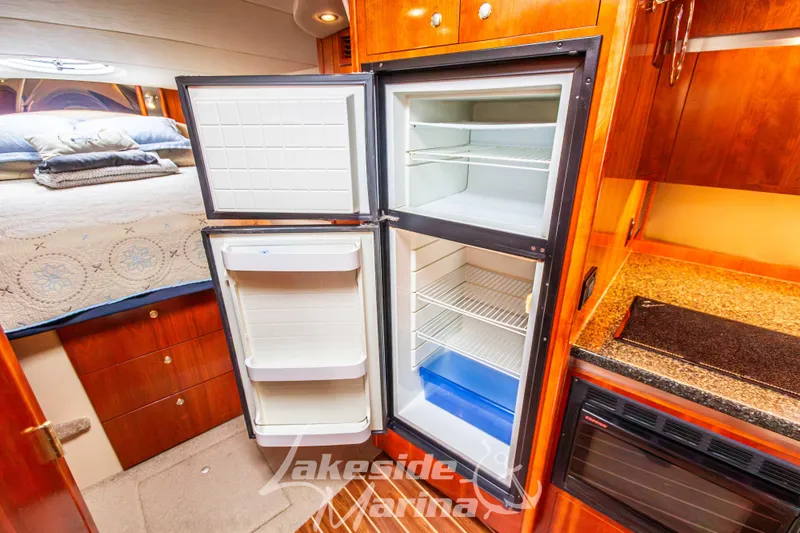 Slide: The Image of 2006 Cruisers Yachts 420 Express interior with open fridge and cozy bedroom view. - 101