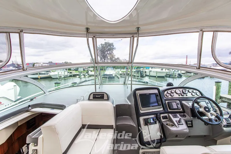 Slide: The Image of 2006 Cruisers Yachts 420 Express helm with modern controls and marina view. - 62