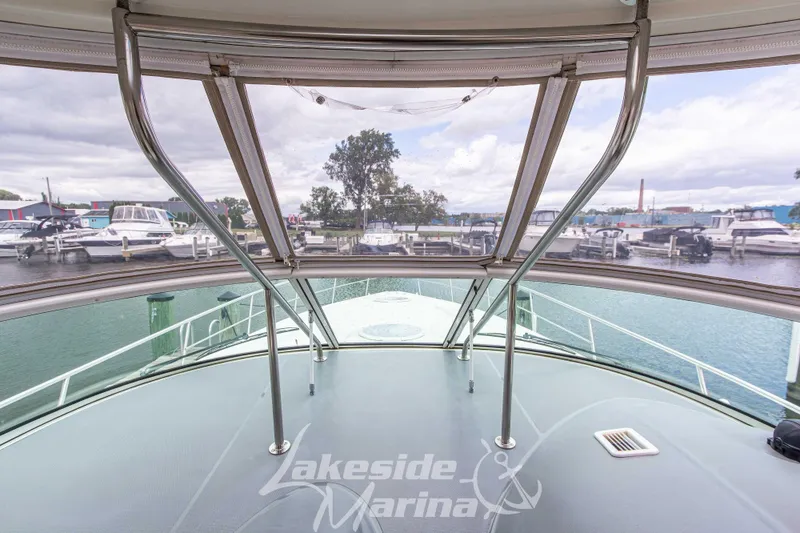 Slide: The Image of 2006 Cruisers Yachts 420 Express at marina, showcasing spacious deck and clear canopy view. - 65