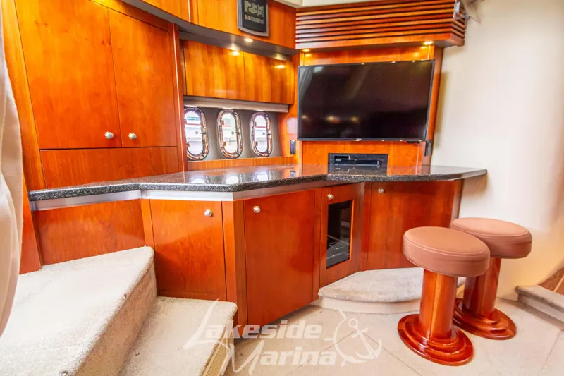 Slide: The Image of 2006 Cruisers Yachts 420 Express interior with wood cabinetry, bar stools, and entertainment area. - 72